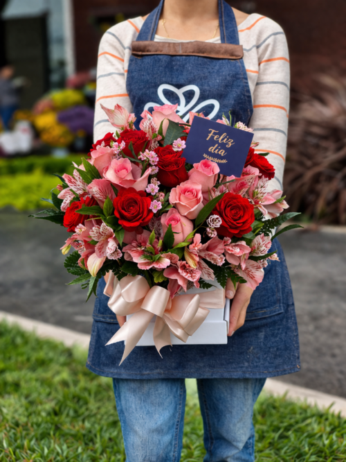 Caja de rosas con flores de complemento y frase