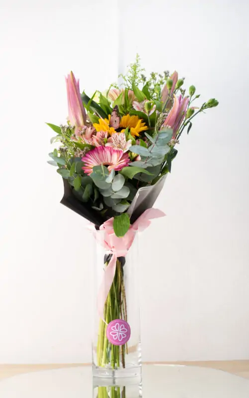 Botella de lirios, gerberas y girasoles con complemento.